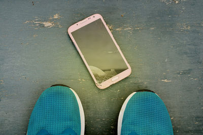 High angle view of shoes by mobile phone on table