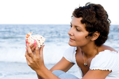 Portrait of young woman looking at sea against sky