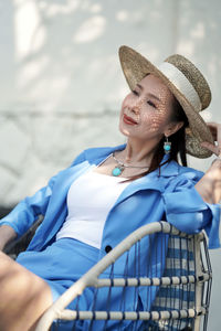 Woman wearing hat sitting against blue sky