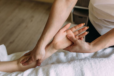 The masseur gives massage to female hand at the spa.