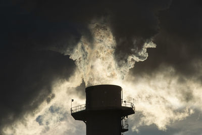 Smoke stacks pour pollution backlit by sunrise