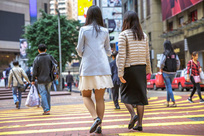 Rear view of women walking on zebra crossing