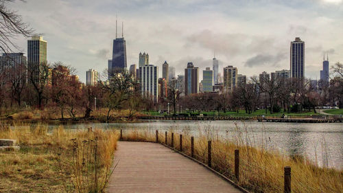 Walkway by buildings against sky in city