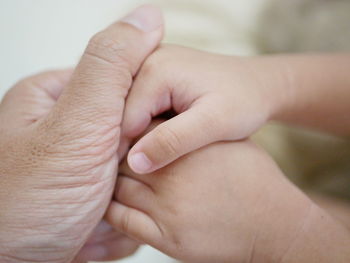Cropped image of man holding baby hands