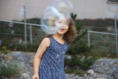 Girl standing by bubbles outdoors