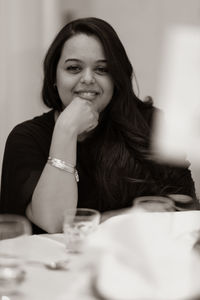Portrait of a smiling young woman sitting on table