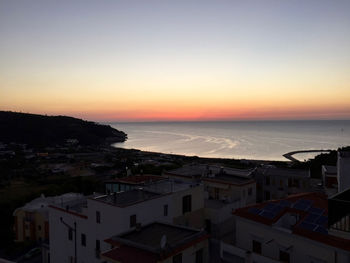 High angle view of townscape by sea against sky during sunset