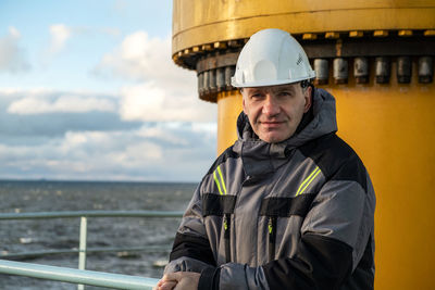 Rear view of engineer standing against sea