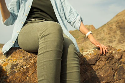 Low section of woman sitting on rock