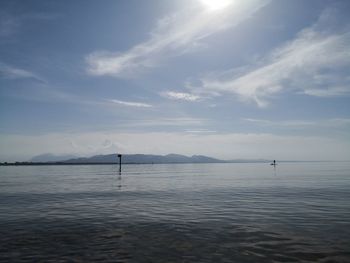 Scenic view of sea against sky with stand up paddler 