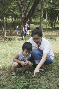 Mid adult woman playing with son on grassy field