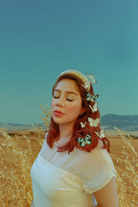 Portrait of a beautiful young woman standing against sky