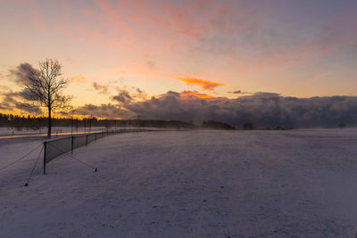 Scenic view of snow covered landscape against sky at sunset