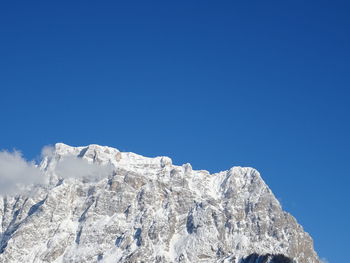 Low angle view of snow against clear blue sky