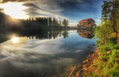 Reflection of trees and buildings in lake against sky