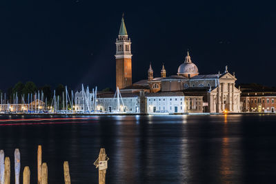 Illuminated city by canal at night