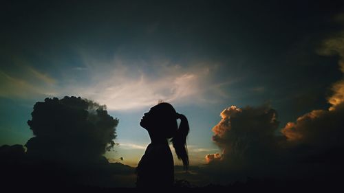 Side view of silhouette woman standing against sky during sunset