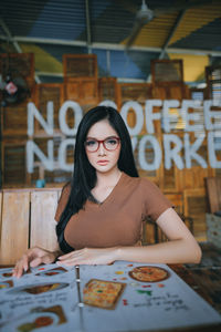 Portrait of young woman sitting on table