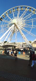 People at amusement park against blue sky