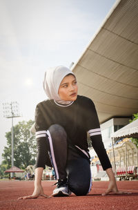 Young woman wearing hijab and sportswear while exercising on sports track