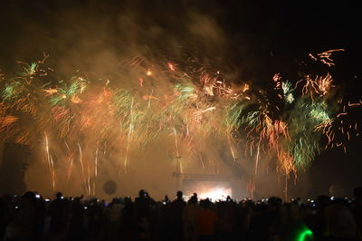 Silhouette crowd by firework display at night