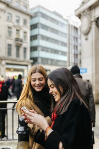 Uk, london, two friends exploring the city, using smart phone