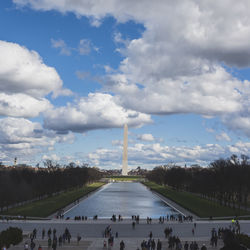 Tourists in front of building against cloudy sky