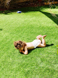 Young child lying naked on field in sunny day