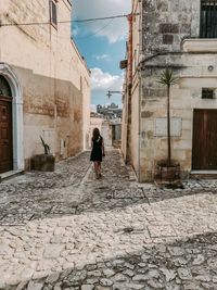 Rear view of woman walking on street amidst buildings in city