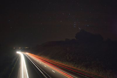 Light trails on road against sky at night