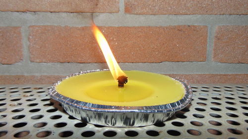 High angle view of lit candle on table against wall