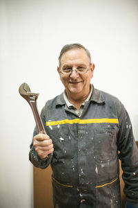 Portrait of smiling senior man holding tool