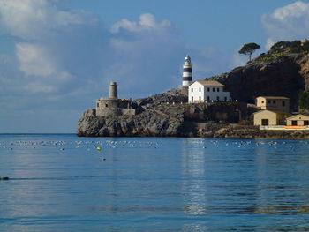 Sea by buildings  and lighthouse against sky