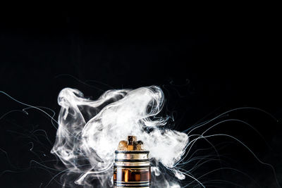 Close-up of smoke emitting from electronic cigarette against gray background