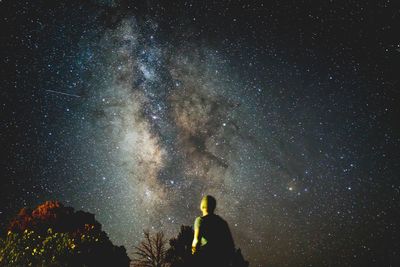 Low angle view of man standing against star field at night