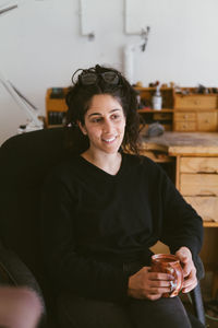 Waist up portrait of seated female jewler in california home studio