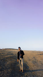 Full length of man standing on field against clear sky