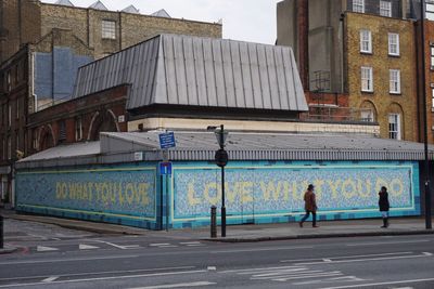 People walking on road by buildings in city