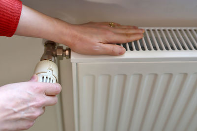 Cropped hands of woman repairing radiator at home
