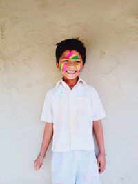 Portrait of smiling boy standing against wall, injoy to festival and keep mind fresh. 