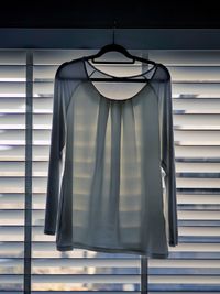 Blouse on coathanger against blinds