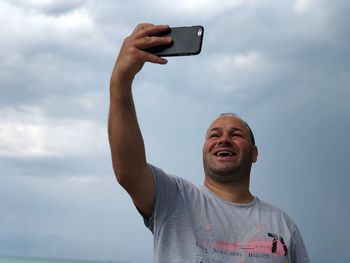 Man taking selfie while standing against cloudy sky