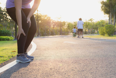 Low section of woman touching leg in pain on road