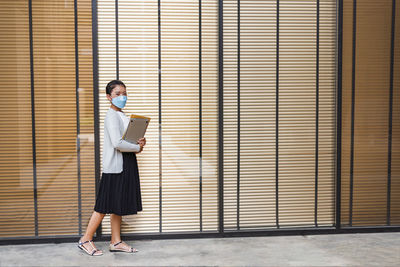 Full length of young woman standing against wall