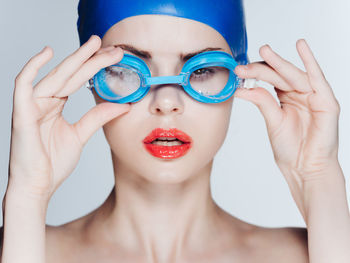 Close-up portrait of young woman wearing mask against white background