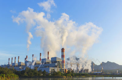 Smoke emitting from factory against sky