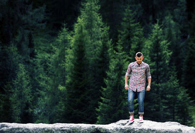 Full length of young woman standing against trees