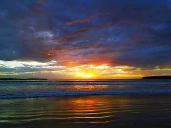 Scenic view of sea against dramatic sky during sunset