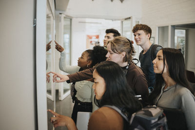 Multiracial students checking result on bulletin board in university