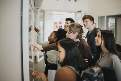 Multiracial students checking result on bulletin board in university